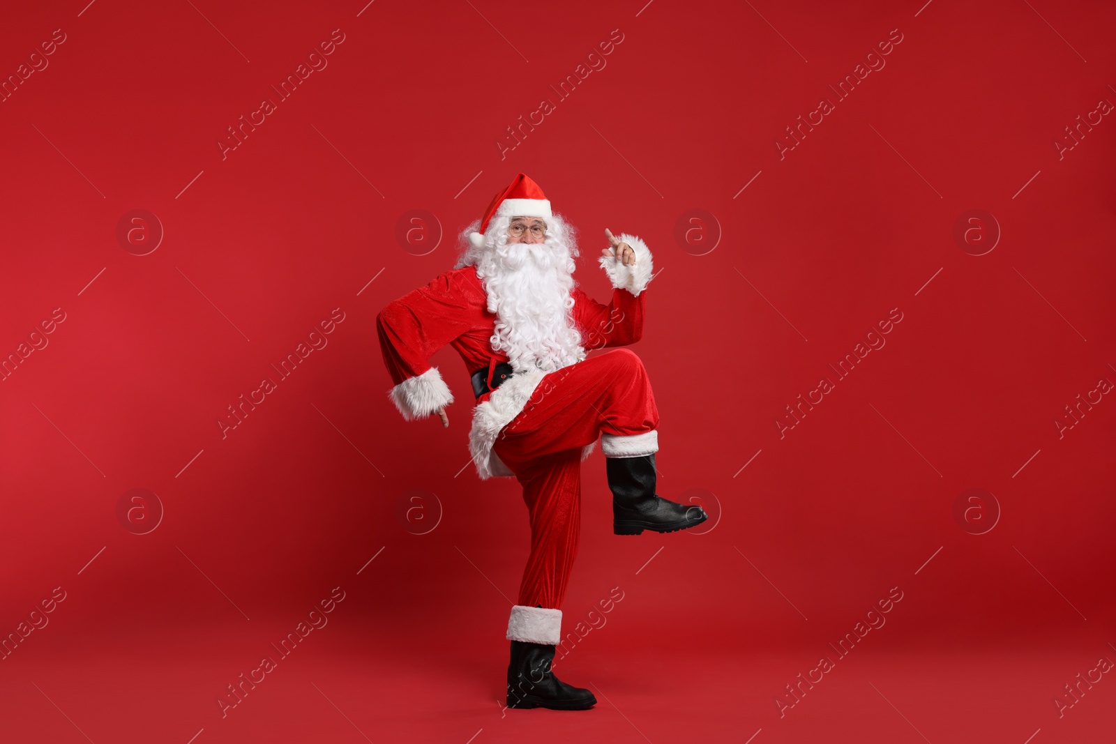 Photo of Merry Christmas. Santa Claus dancing on red background