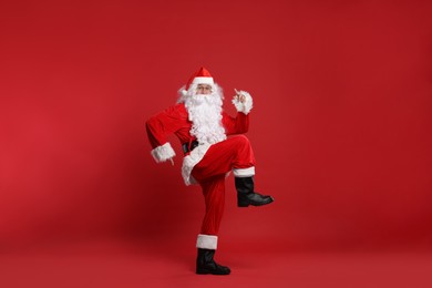 Photo of Merry Christmas. Santa Claus dancing on red background