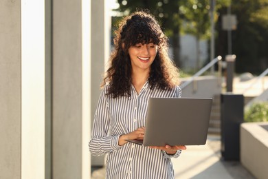 Happy young woman using modern laptop outdoors