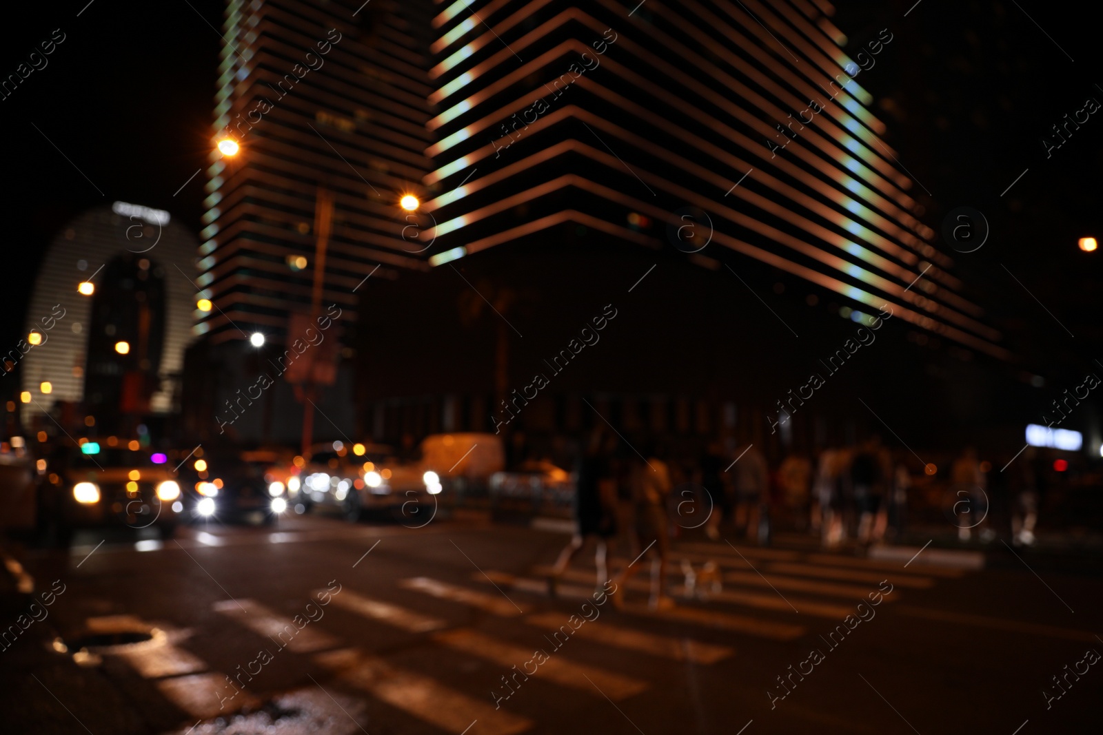 Photo of BATUMI, GEORGIA - JUNE 09, 2022: Blurred view of people crossing street in city. Night life