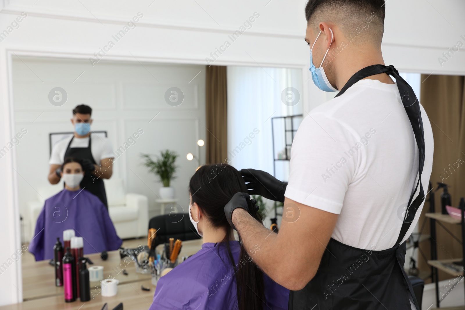 Photo of Professional stylist working with client in salon, space for text. Hairdressing services during Coronavirus quarantine