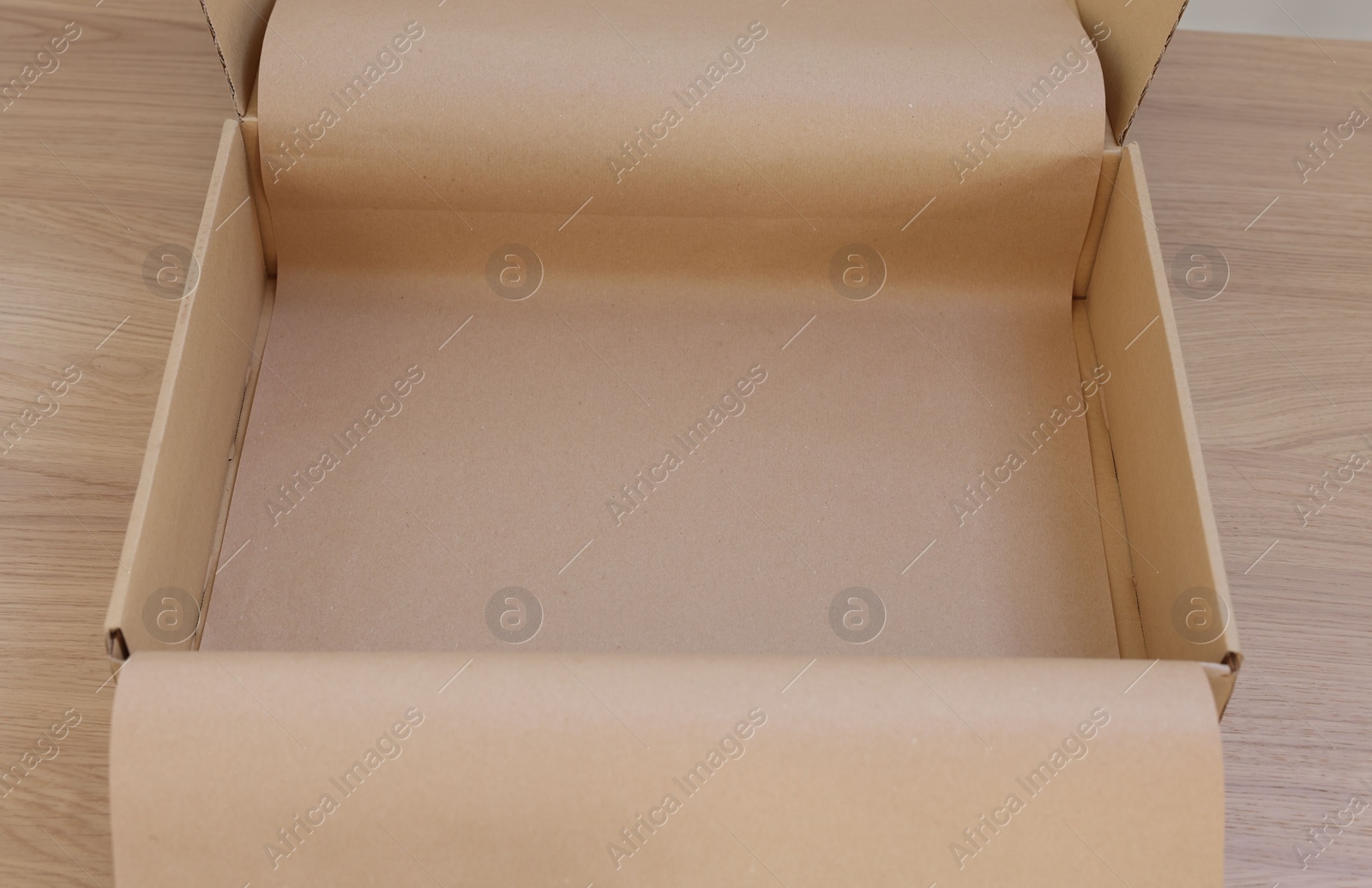 Photo of Empty cardboard box with kraft paper on wooden table, closeup. Delivery service