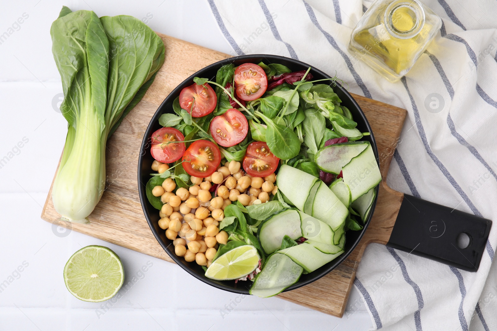 Photo of Tasty salad with chickpeas, cherry tomatoes and cucumbers served on white tiled table, flat lay