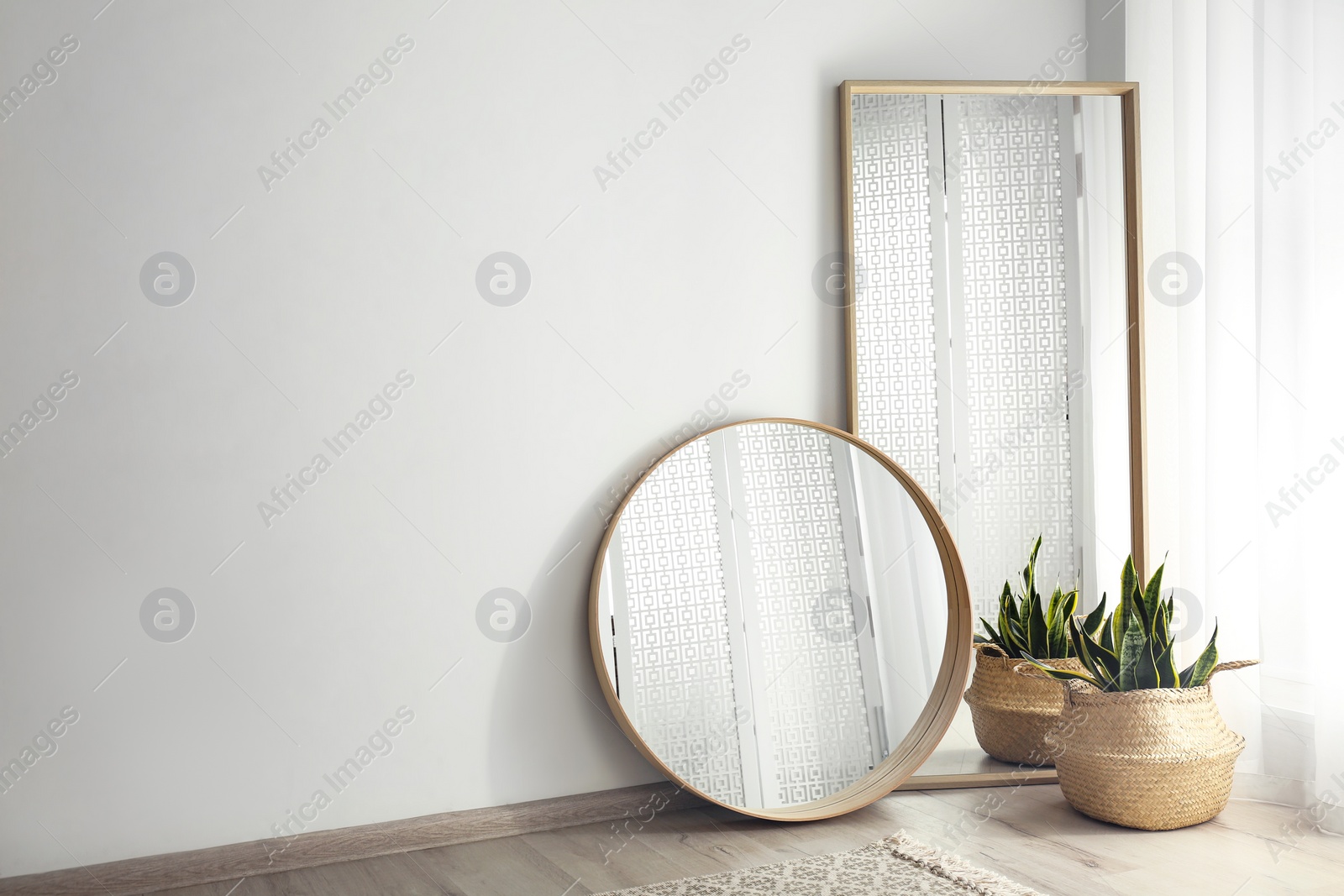 Photo of Mirrors and potted plant near window in light room