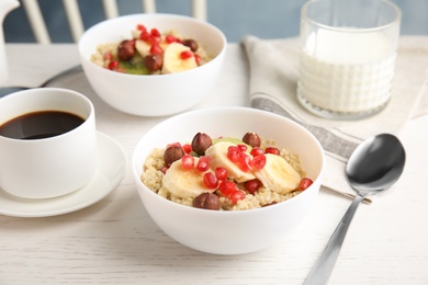 Photo of Quinoa porridge with hazelnuts, kiwi, banana and pomegranate seeds served for breakfast on white wooden table