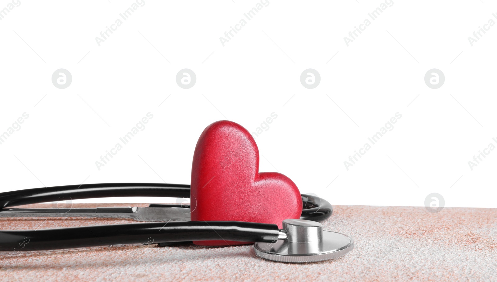 Photo of Stethoscope and red heart on color textured table against white background, space for text