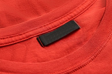 Photo of Blank clothing label on red T-shirt, closeup