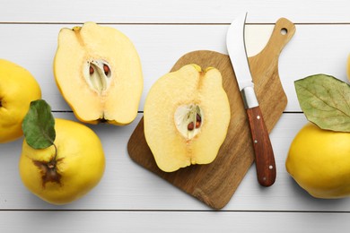 Tasty ripe quince fruits and knife on white wooden table, flat lay