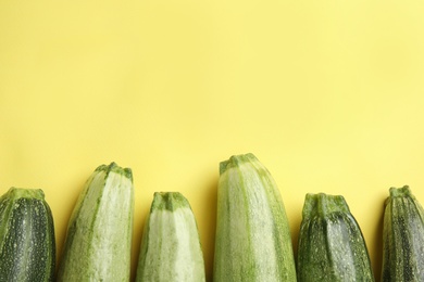 Fresh ripe green zucchinis on yellow background, flat lay. Space for text