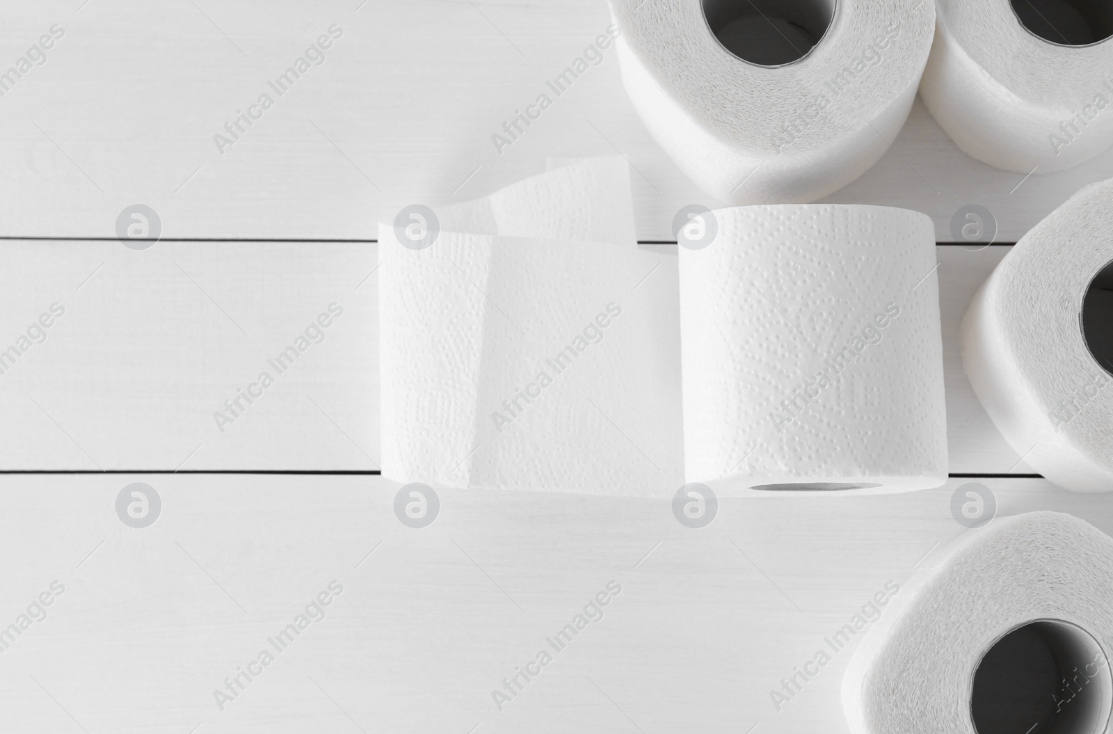 Photo of Many soft toilet paper rolls on white wooden table, flat lay. Space for text