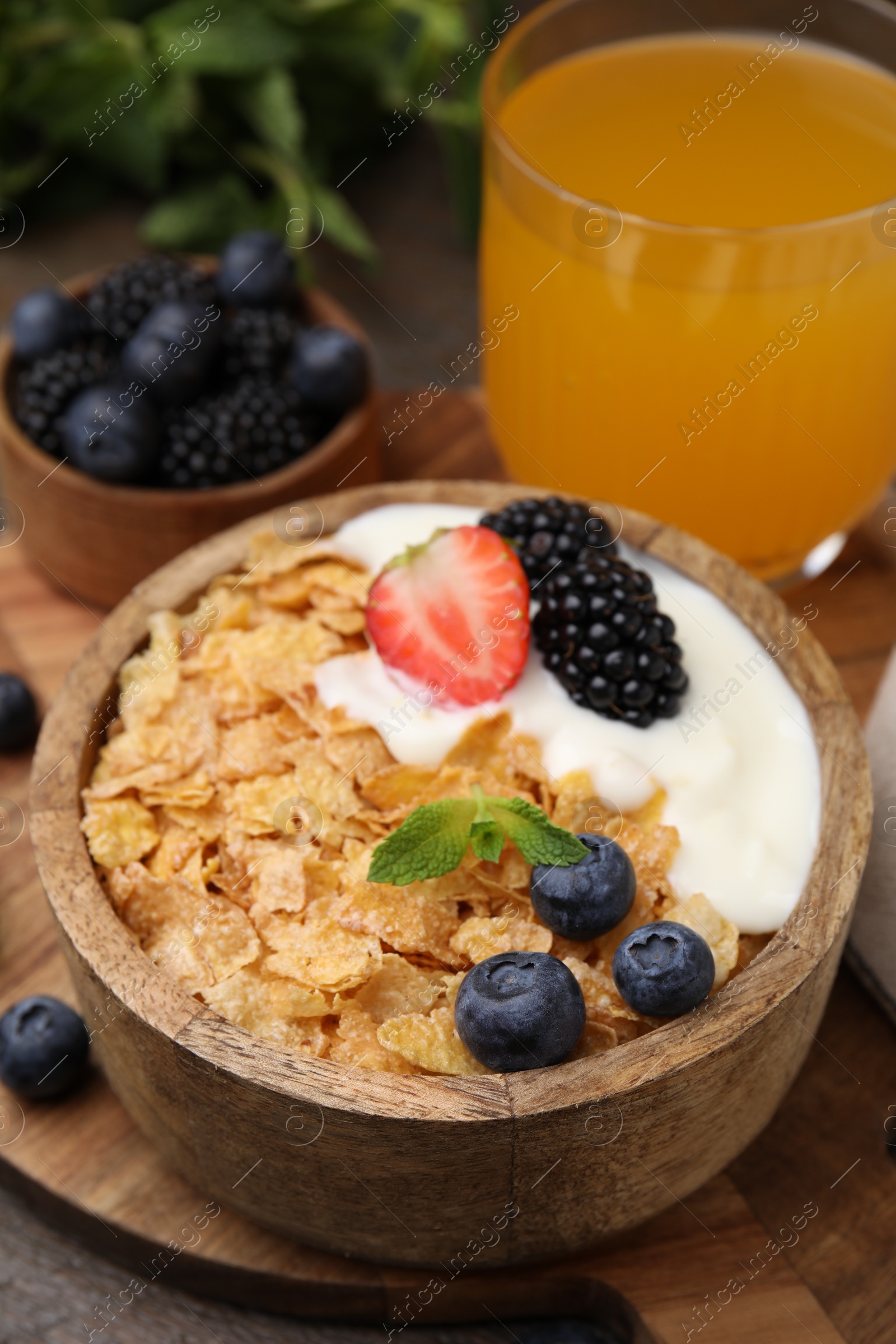 Photo of Delicious crispy cornflakes, yogurt and fresh berries in bowl on table, closeup. Healthy breakfast