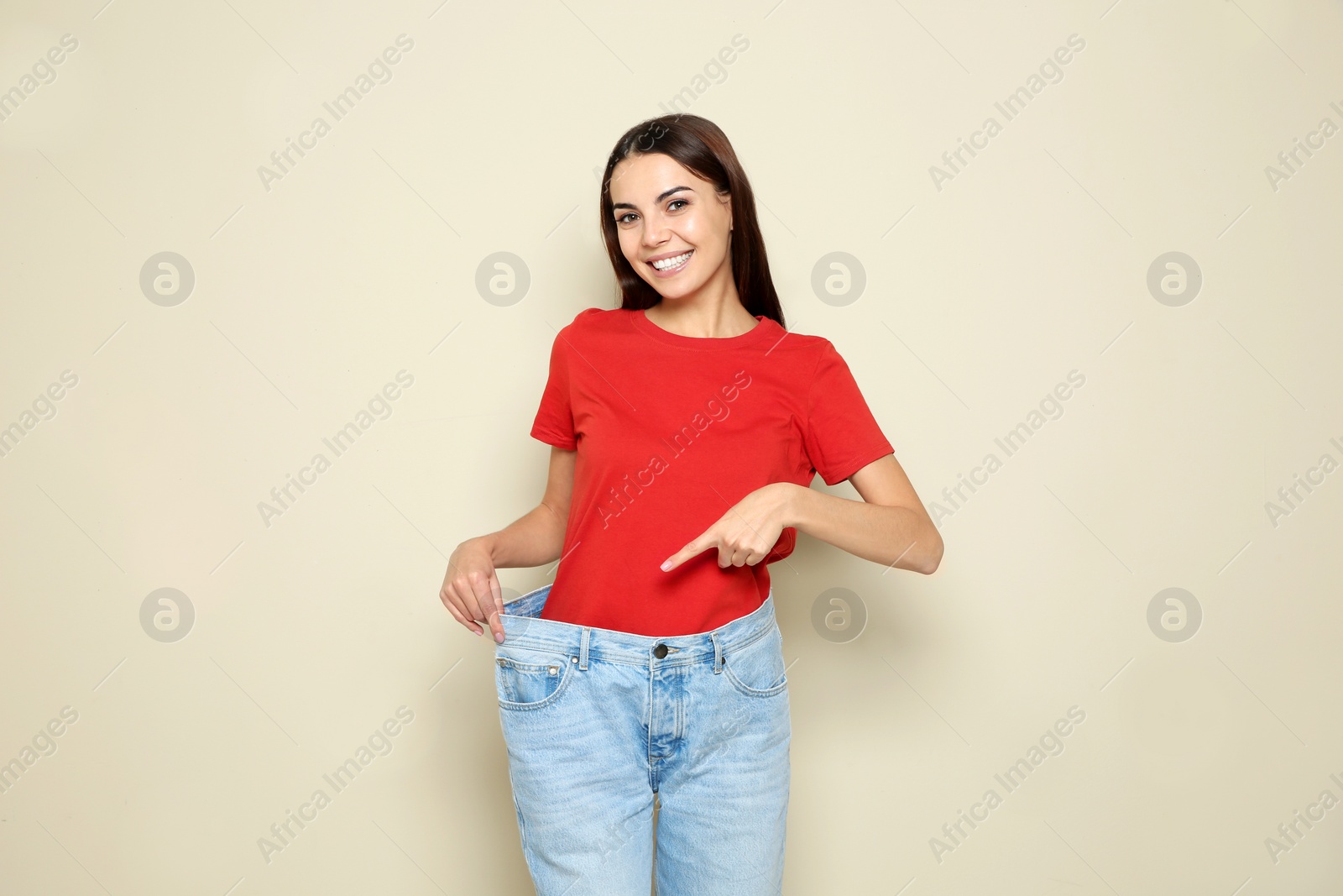 Photo of Slim woman in oversized jeans on color background. Weight loss