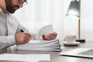 Photo of Man working with documents at wooden table in office, closeup