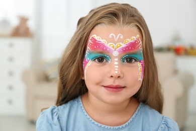 Photo of Cute little girl with face painting indoors