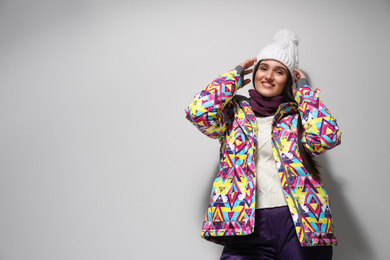 Woman wearing stylish winter sport clothes on light grey background