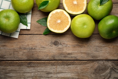 Whole and cut sweetie fruits on wooden table, flat lay. Space for text