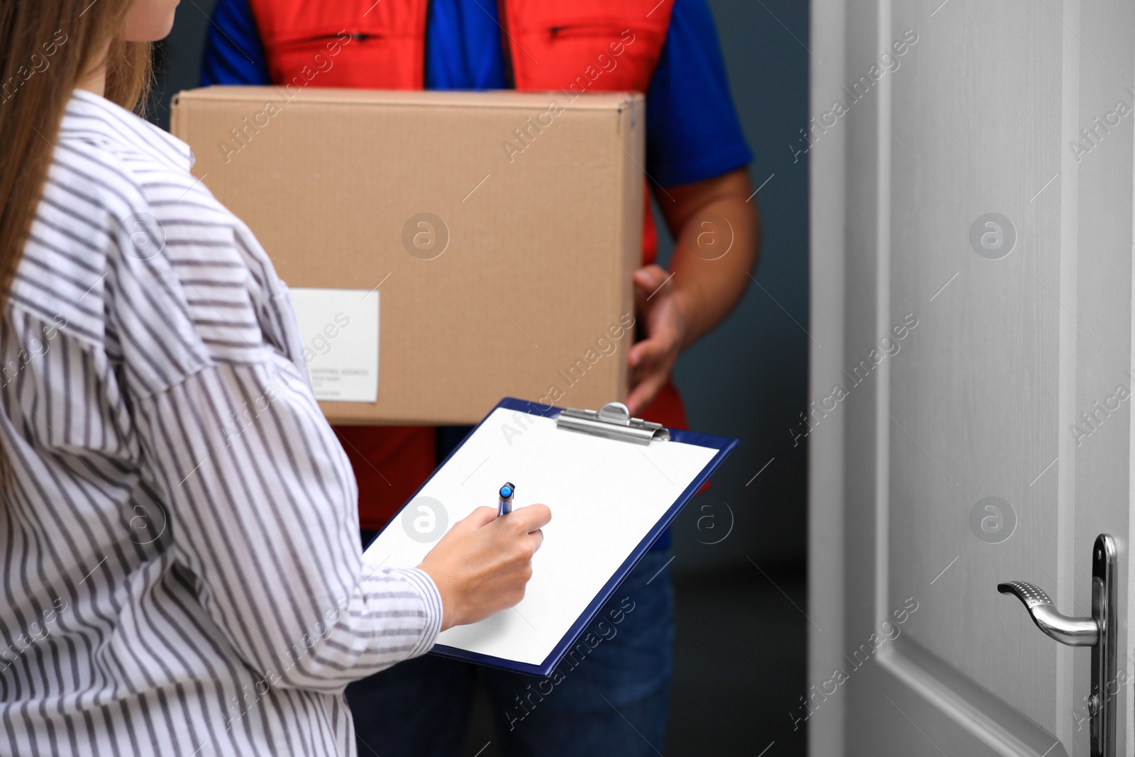 Photo of Woman signing for delivered parcel on doorstep, closeup