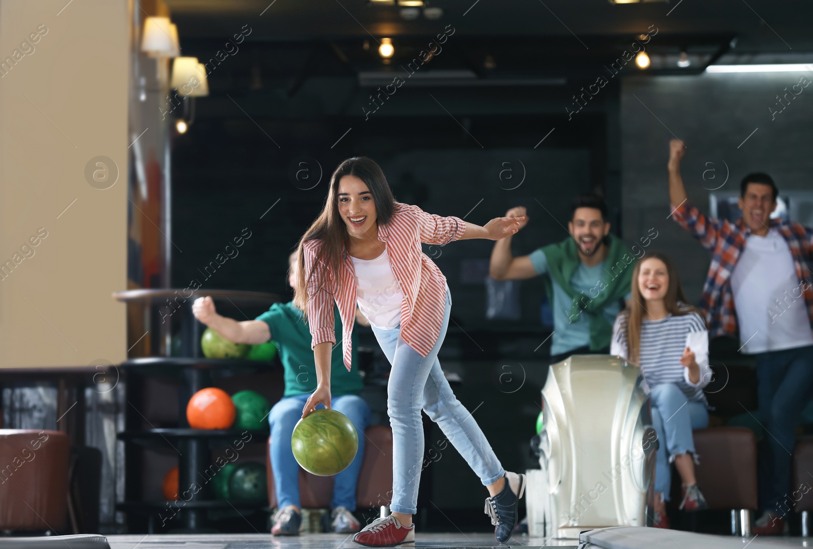 Photo of Young woman throwing ball and spending time with friends in bowling club