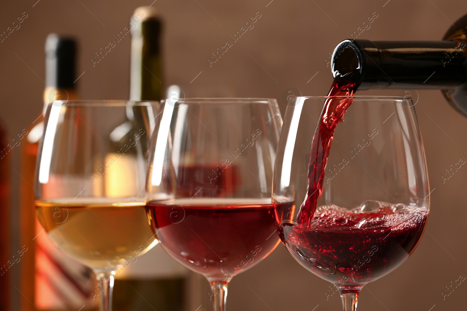 Photo of Pouring wine from bottle into glass on blurred background, closeup