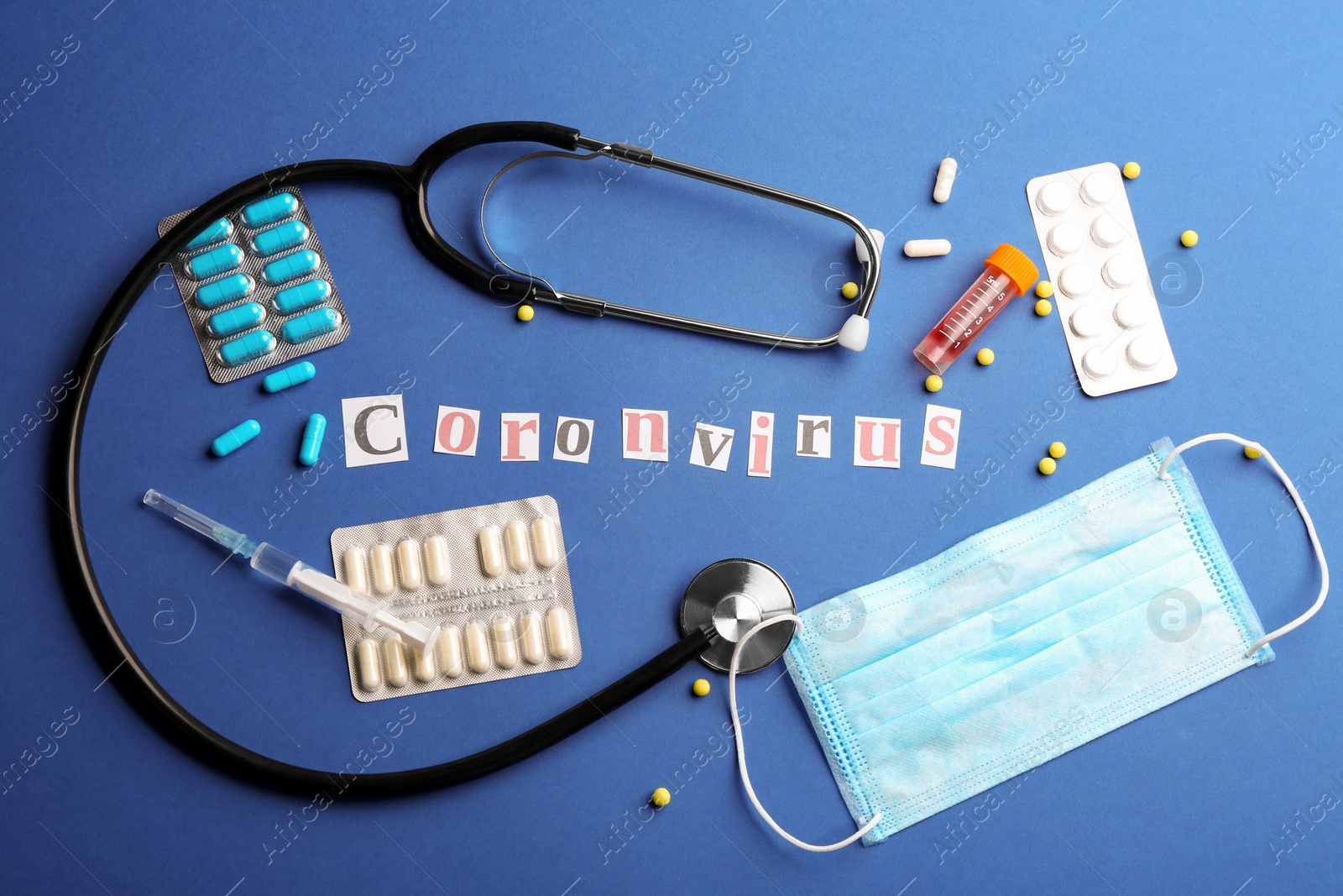 Photo of Flat lay composition with word CORONAVIRUS, stethoscope and medicine on blue background