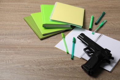 Photo of Gun and school stationery on wooden table, space for text