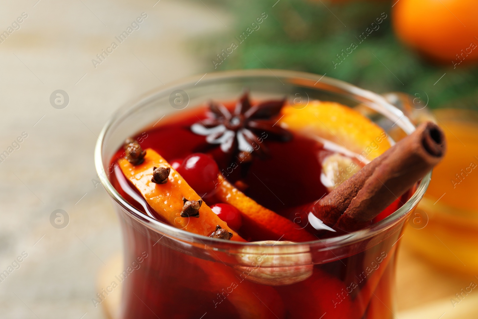 Photo of Glass cup of tasty mulled wine with spices, closeup