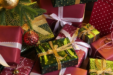 Photo of Pile of gift boxes near decorated Christmas tree