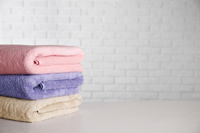 Photo of Stack of clean bath towels on white wooden table. Space for text