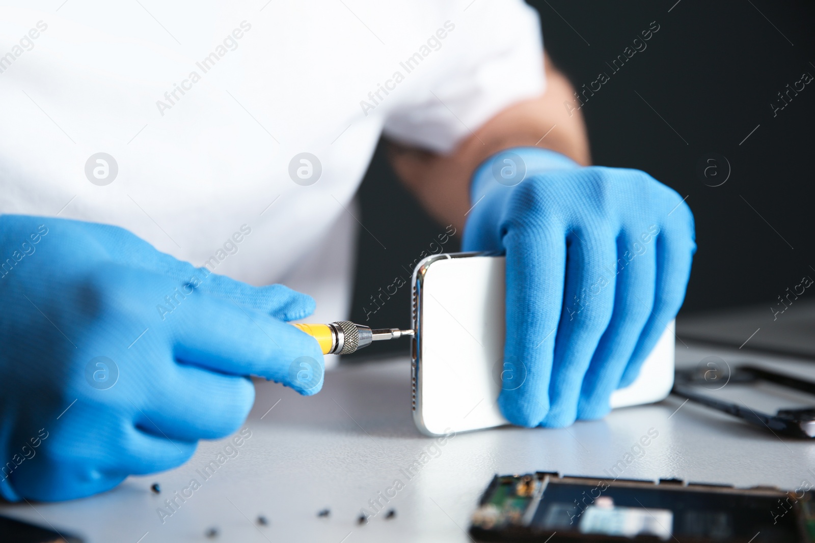 Photo of Technician repairing mobile phone at table, closeup