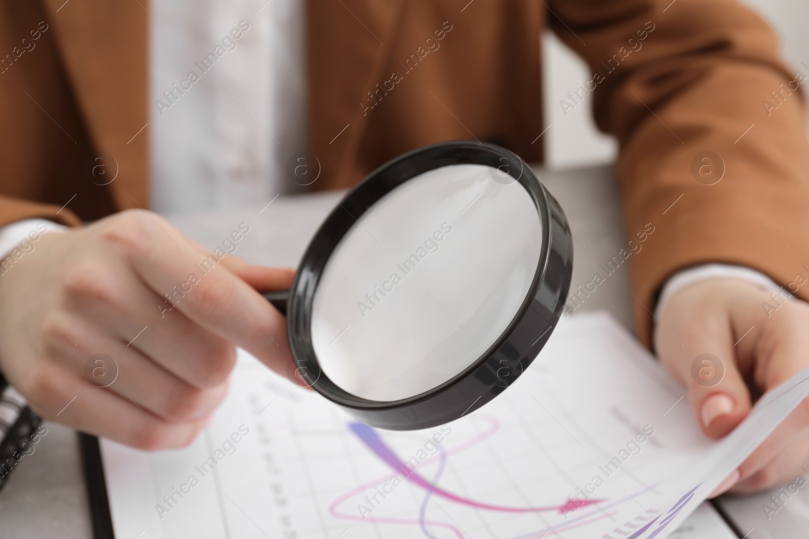 Photo of Woman looking at document through magnifier at table, closeup. Searching concept