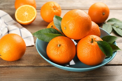 Many delicious ripe oranges on wooden table