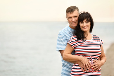 Happy mature couple spending time together on sea beach. Space for text