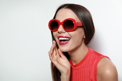 Photo of Beautiful woman in stylish sunglasses on light background