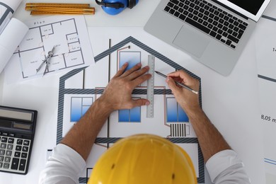 Photo of Architect working with construction drawings at white table, top view