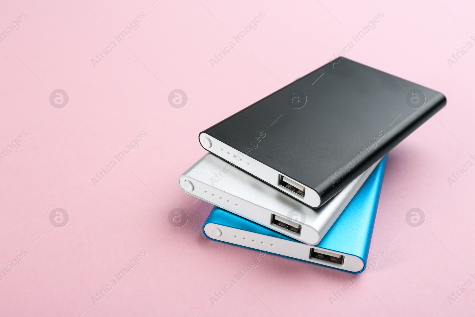 Photo of Modern external portable chargers on pink background