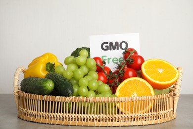 Photo of Tasty fresh GMO free products and paper card on grey table against light background