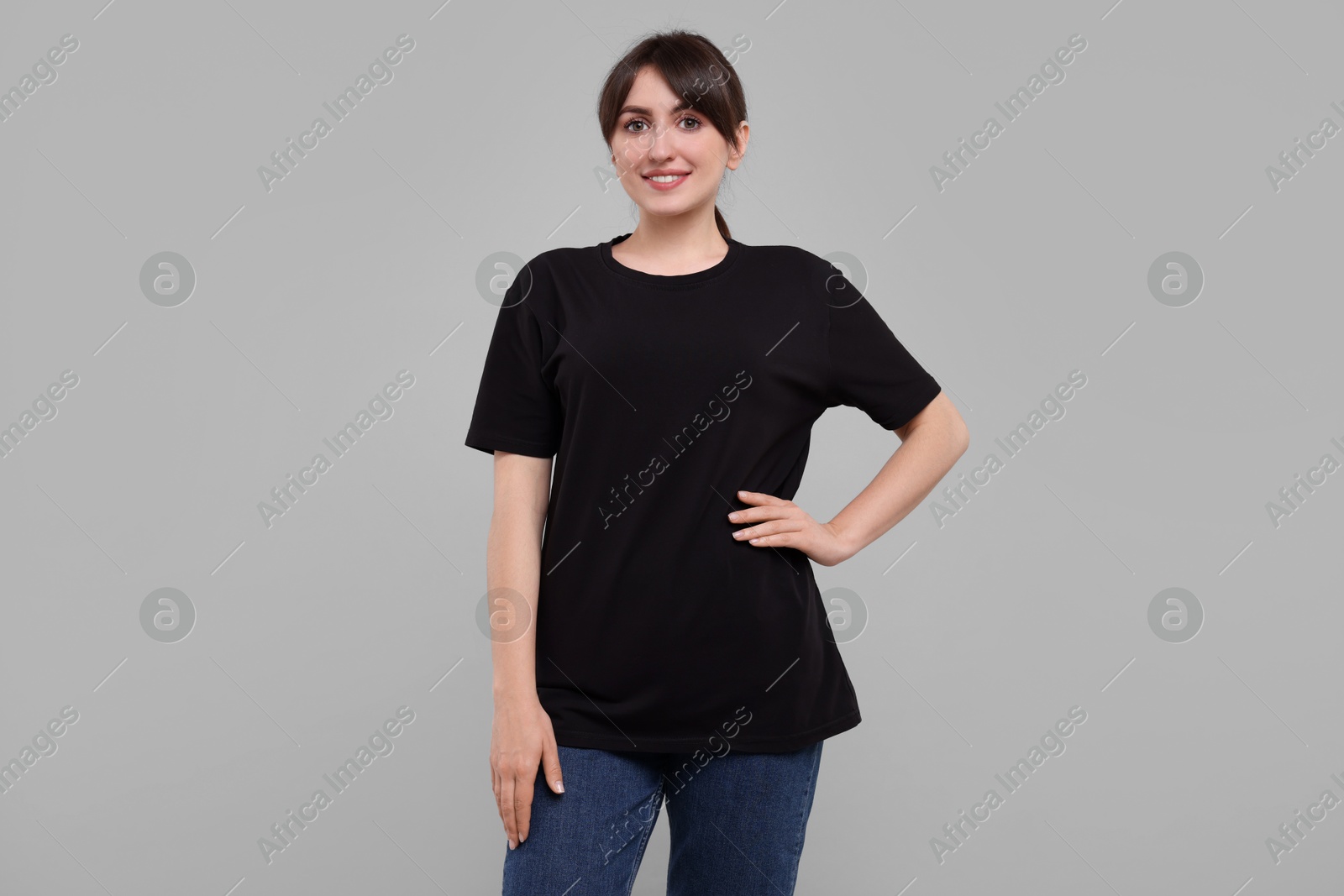 Photo of Smiling woman in stylish black t-shirt on light grey background