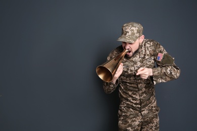 Military man shouting into megaphone on gray background