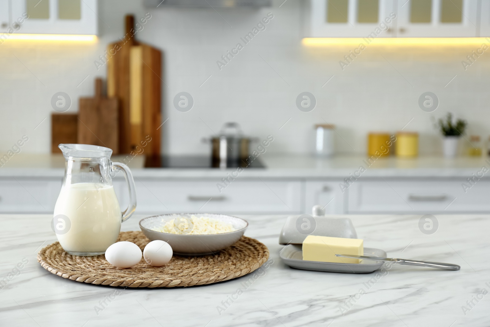 Photo of Different dairy products and eggs on white table in modern kitchen. Space for text