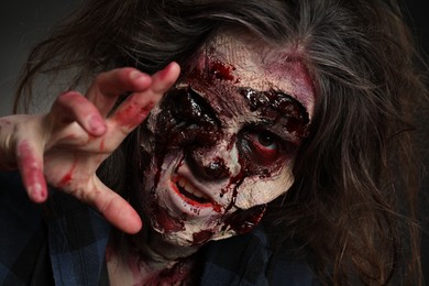 Photo of Scary zombie on dark background, closeup. Halloween monster