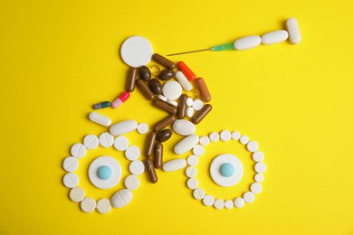 Photo of Sportsman, bike and syringe made of pills on yellow background, flat lay. Using doping in cycling sport concept