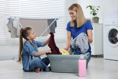 Mother and daughter taking out dirty clothes from basket in bathroom