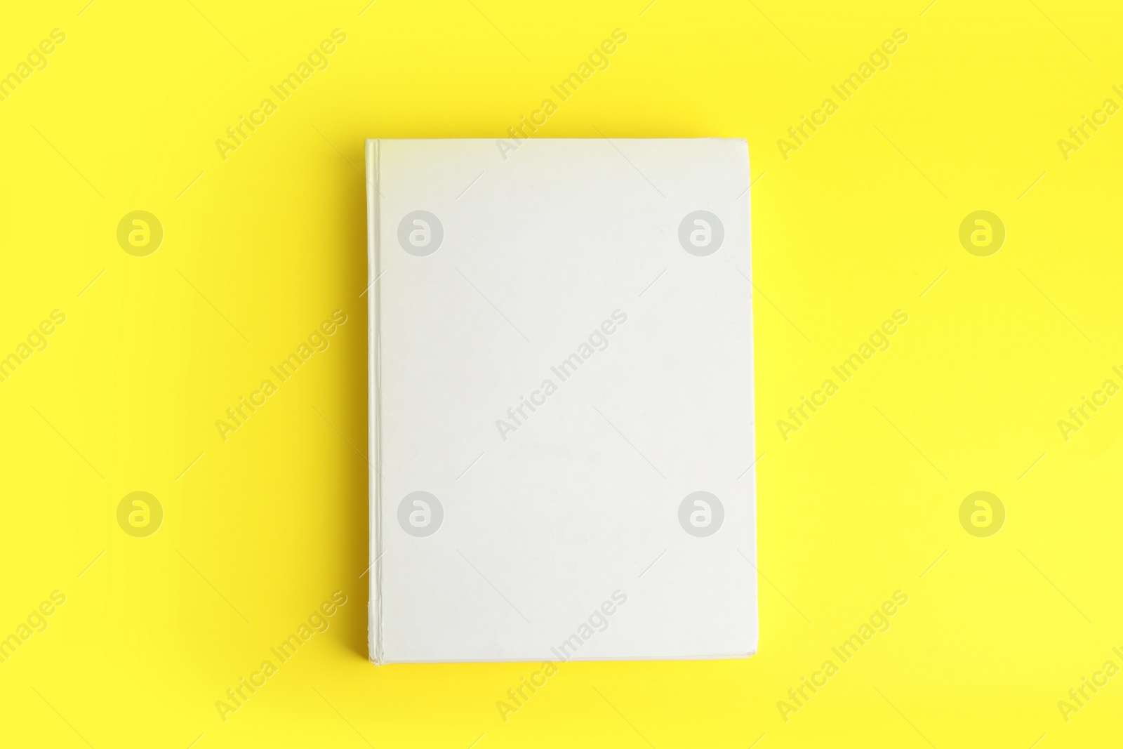 Photo of Book with blank cover on yellow background, top view