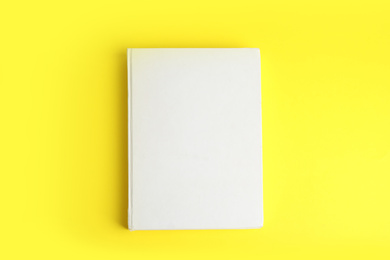 Photo of Book with blank cover on yellow background, top view