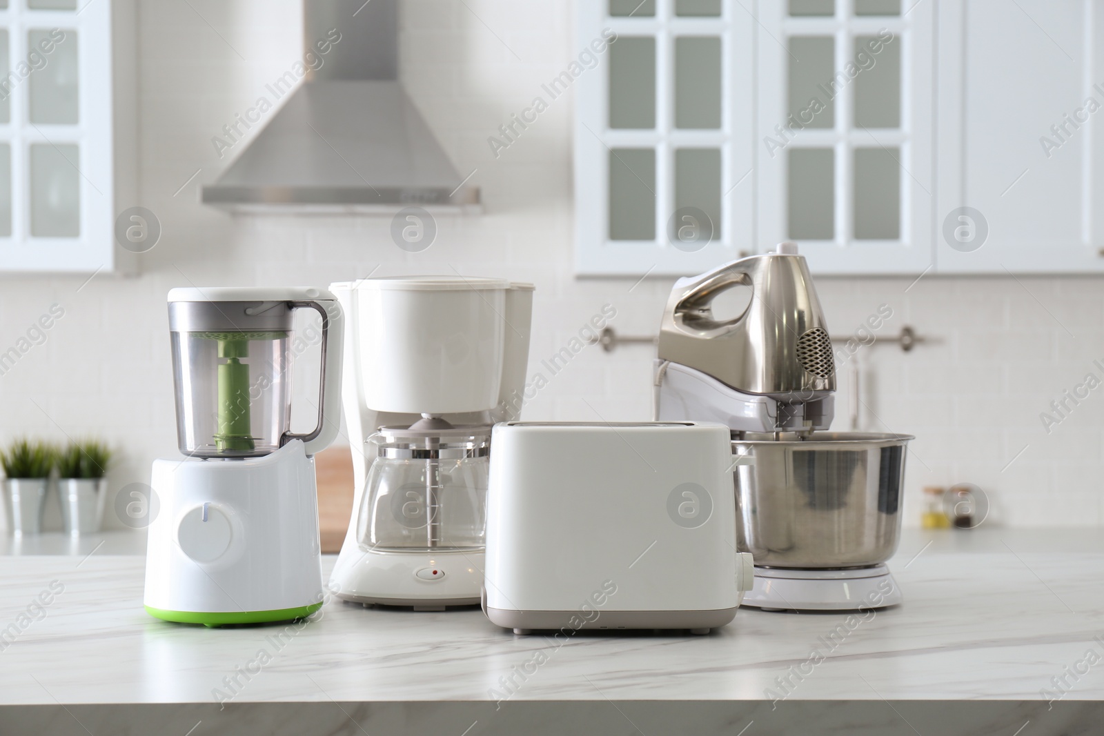 Photo of Modern toaster and other home appliances on white marble table in kitchen