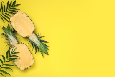 Photo of Halves of ripe pineapple and green leaves on yellow background, flat lay. Space for text