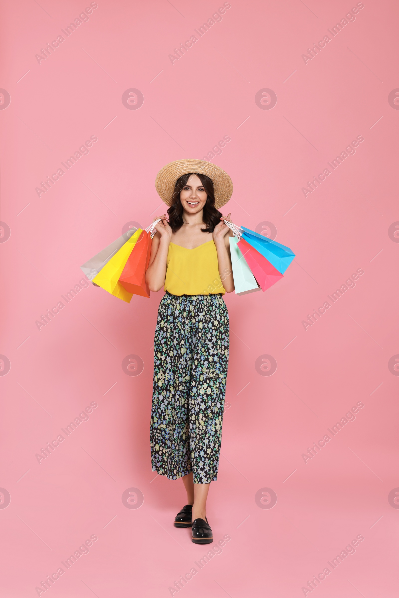 Photo of Beautiful young woman with paper shopping bags on pink background