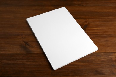 Photo of Stack of blank paper sheets on wooden table. Brochure design