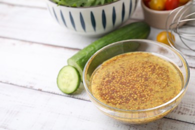 Tasty vinegar based sauce (Vinaigrette) in bowl and cucumber on wooden rustic table, closeup. Space for text