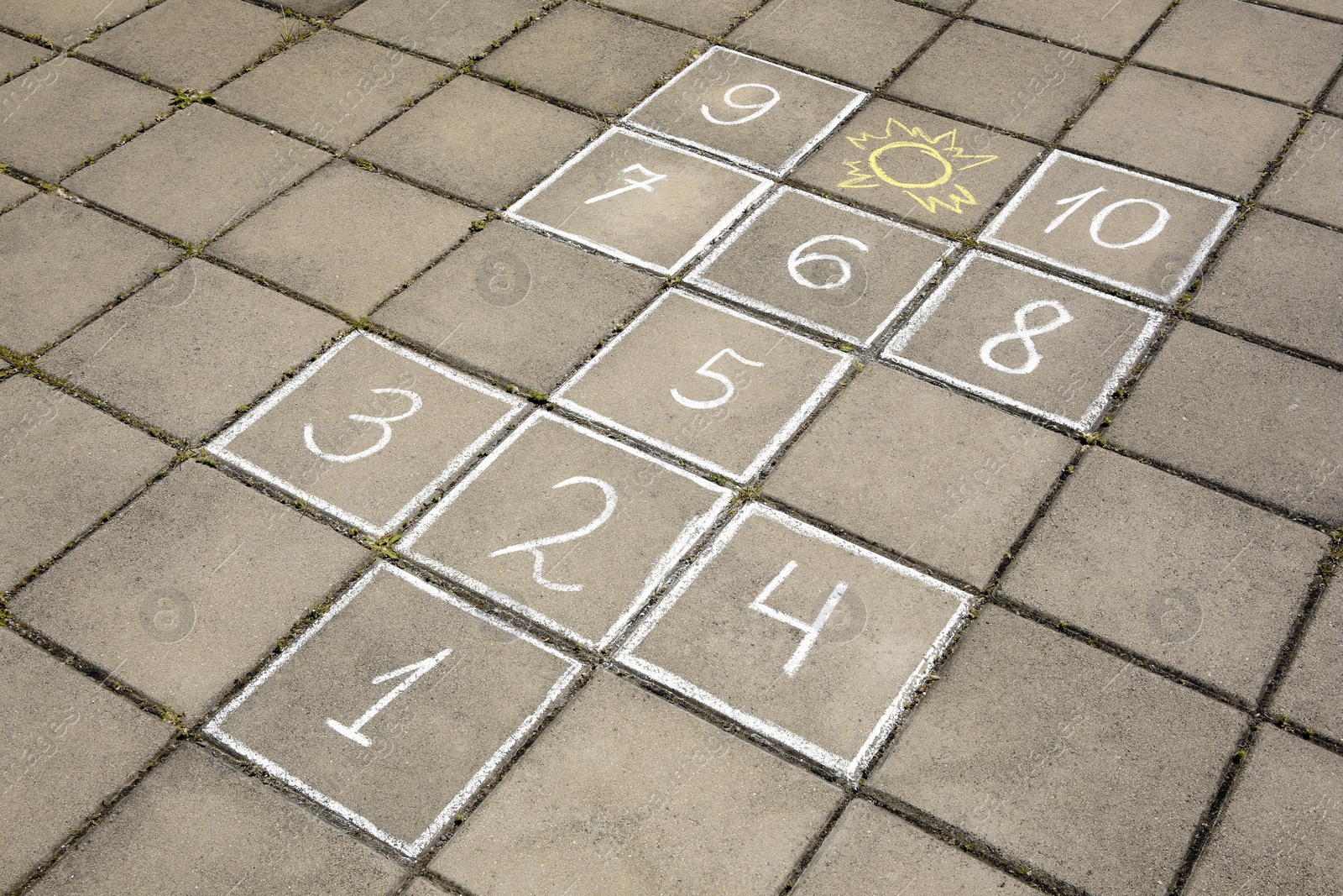 Photo of Hopscotch drawn with white chalk on street tiles outdoors